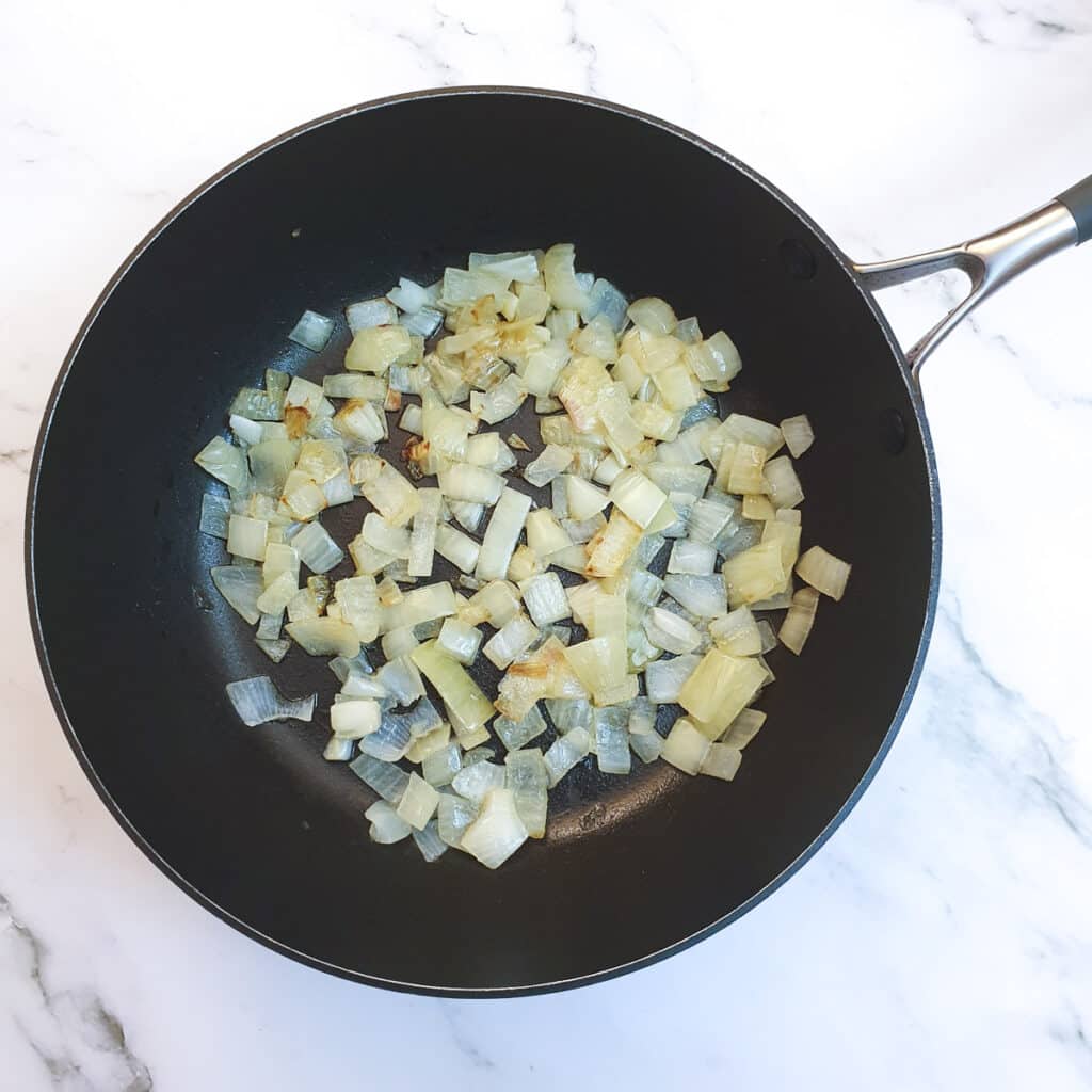 Chopped onions frying in a pan.