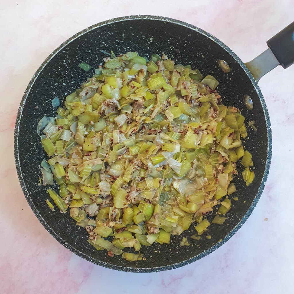 Chopped leeks, celery and walnuts in a saucepan.