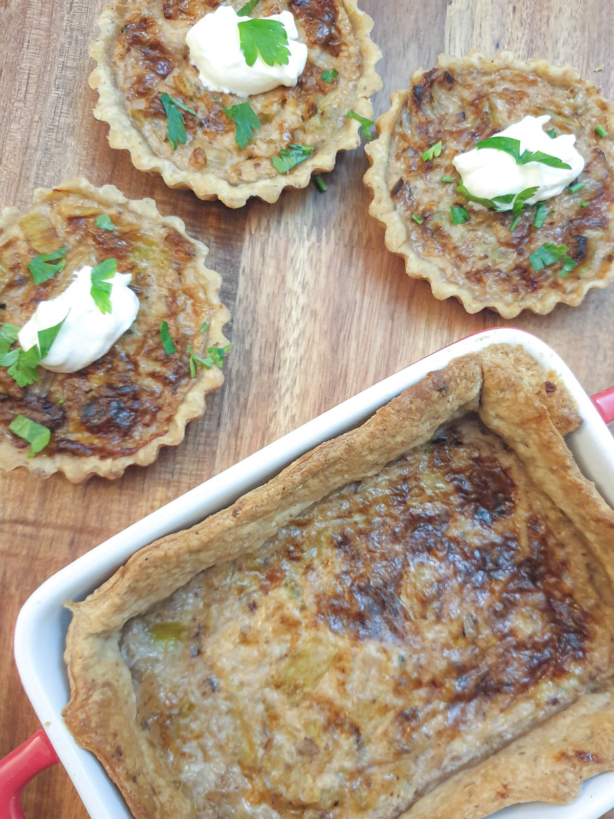 Three small round stilton and walnut tarts next to a larger square tart.