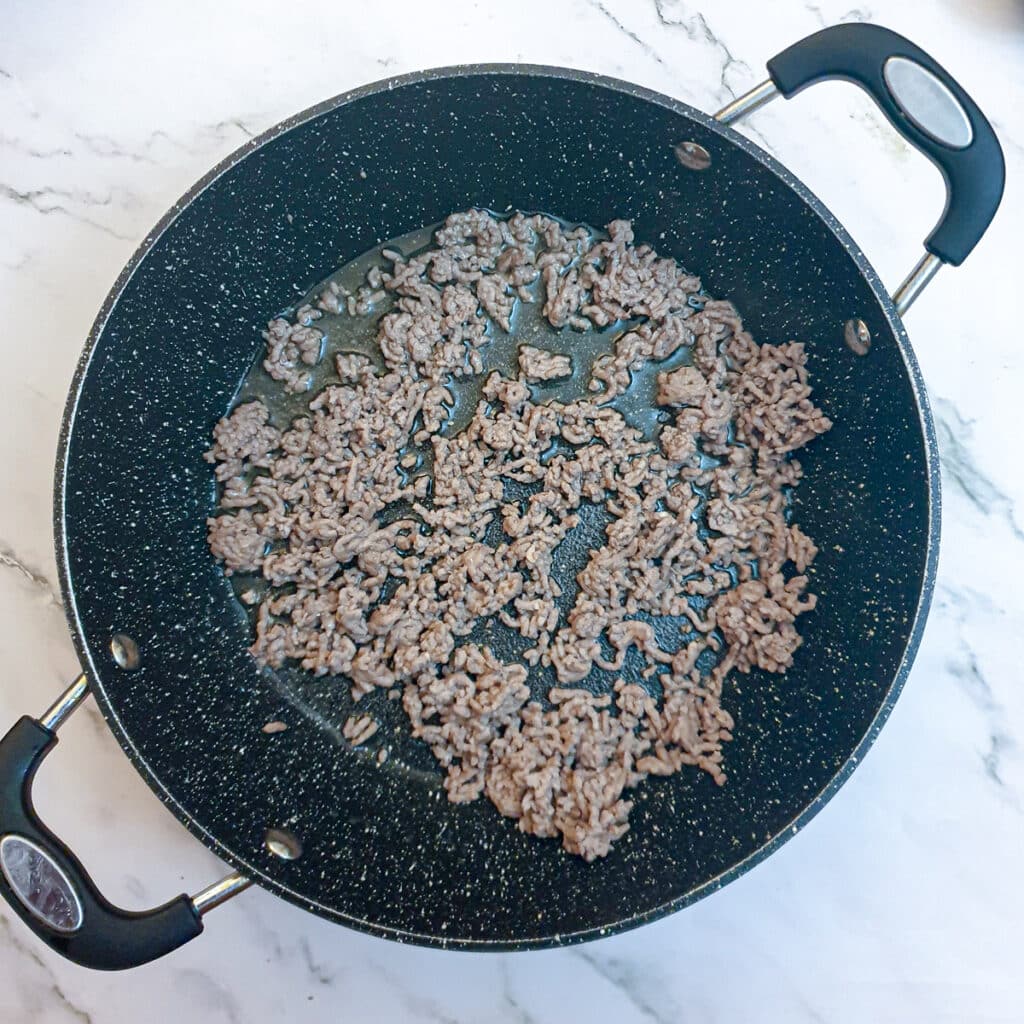 Lamb mince being browned in a frying pan.