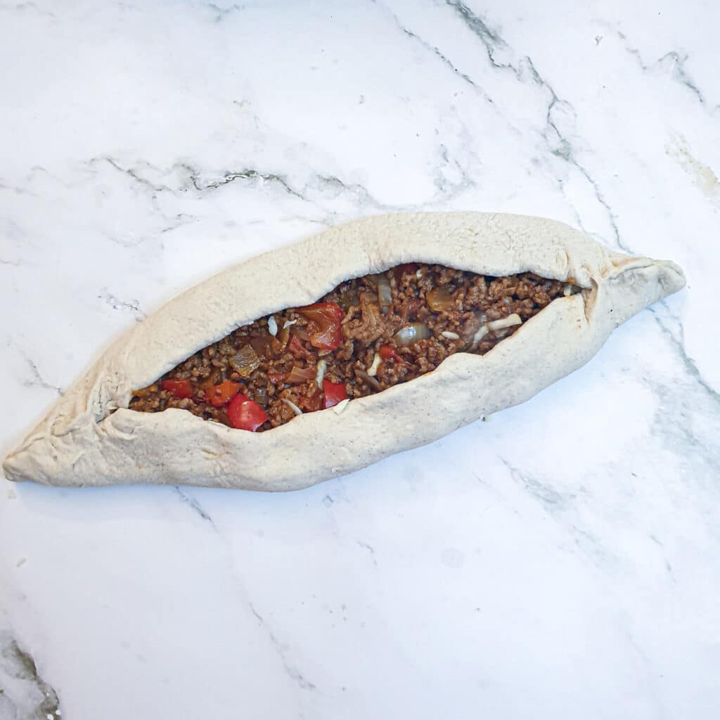 A lamb pide folded and formed into a boat shape.