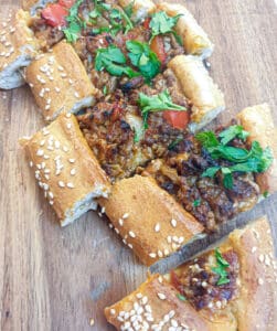 Slices of lamb pide on a wooden platter.