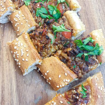 Slices of lamb pide on a wooden platter.