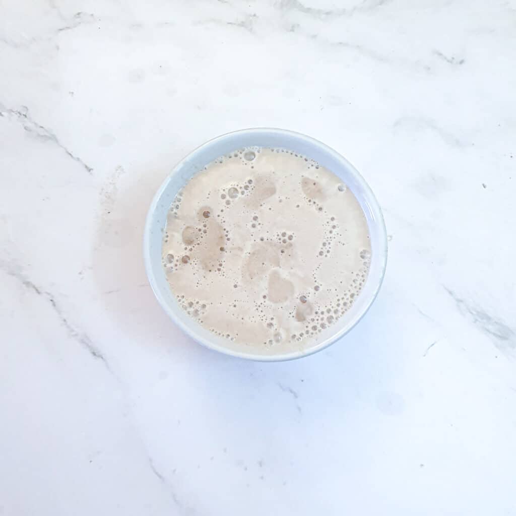 Instant yeast frothing in a small glass bowl of warm water.