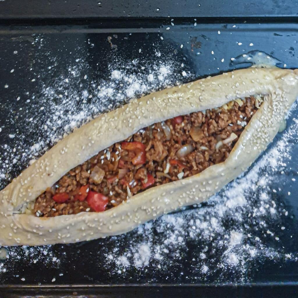 A lamb pide on a baking sheet.