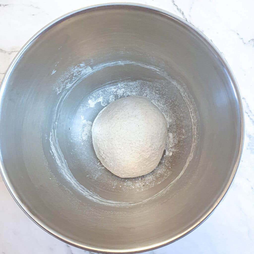 A ball of unrisen dough in a mixing bowl.