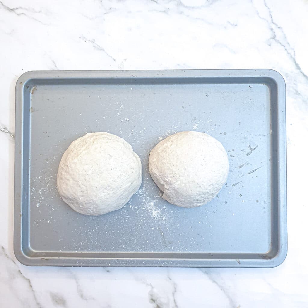 Two balls of dough on a baking tray.