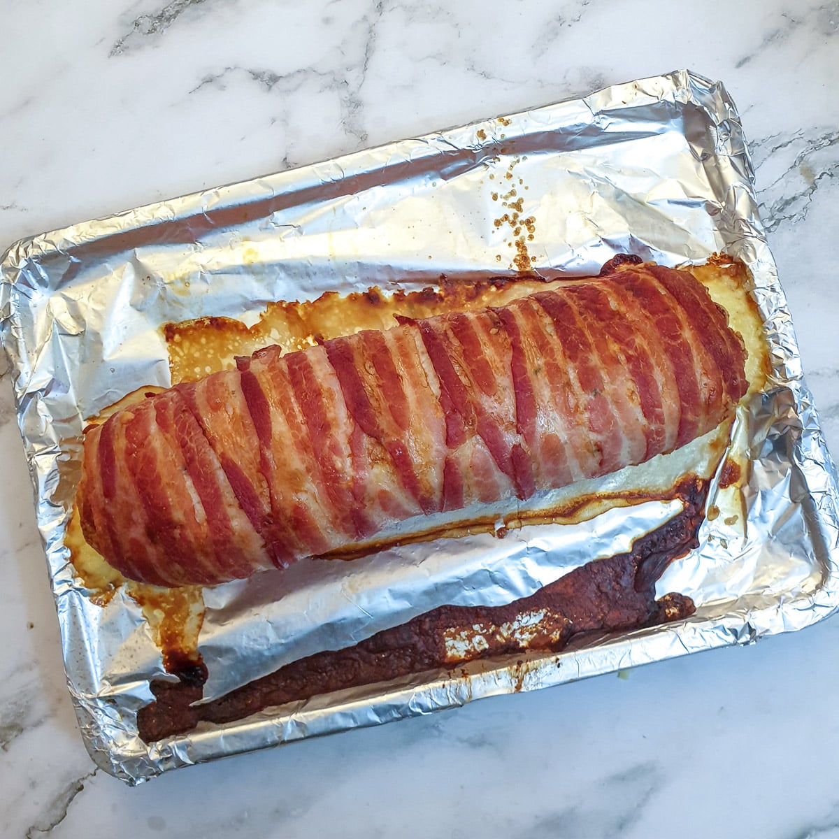 Cooked chicken and bacon meatloaf on a baking tray.