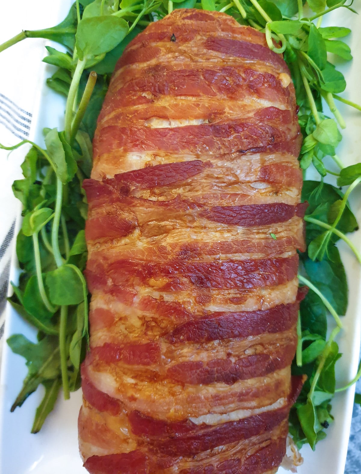 Top view of a chicken and bacon meatloaf, showing the crispy bacon wrapping.