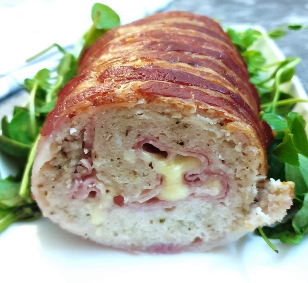 A cross-section view of a chicken and bacon meatloaf, showing the ham and cheese inside.