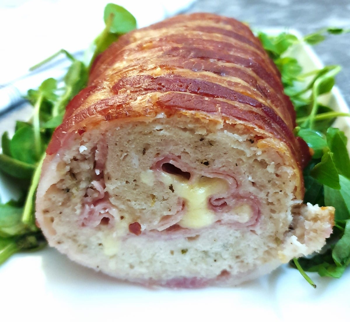 A cross-section view of a chicken and bacon meatloaf, showing the ham and cheese inside.