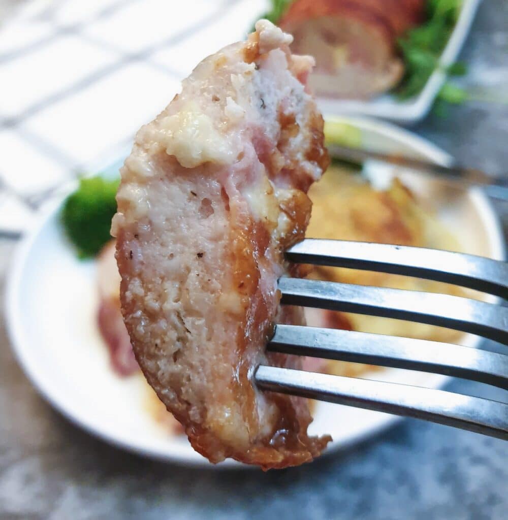 A bite-sized piece of chicken and bacon meatloaf on a fork.