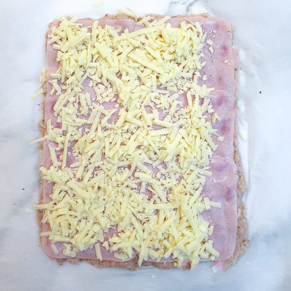 Grated cheese sprinkled onto the ham and chicken.