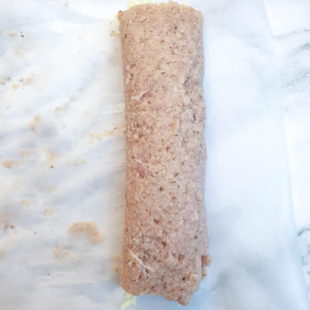 Minced chicken formed into a sausage shape, enclosing ham and cheese.