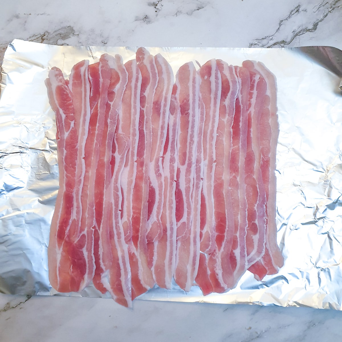 Bacon rashers arranged in a rectangle on a sheet of tinfoil.