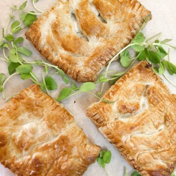 Three chicken and mushroom bakes on a tray, garnished with green pea shoots.