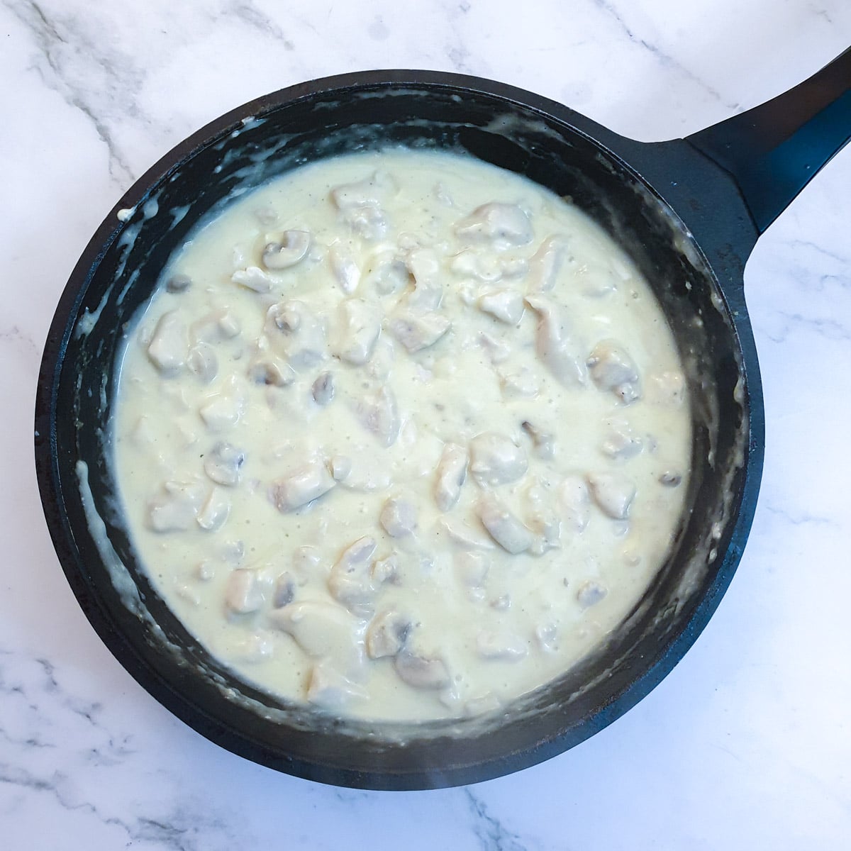 Chicken and mushroom filling in a frying pan after the addition of cream and cream cheese.