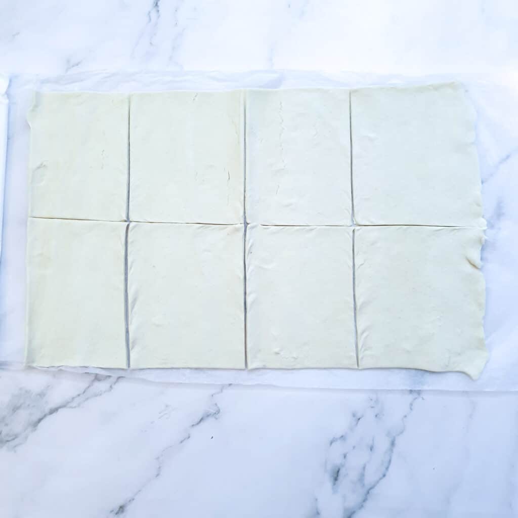 A sheet of puff pastry cut into 8 rectangles.