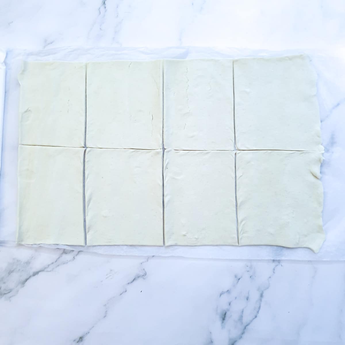 A sheet of puff pastry cut into 8 rectangles.