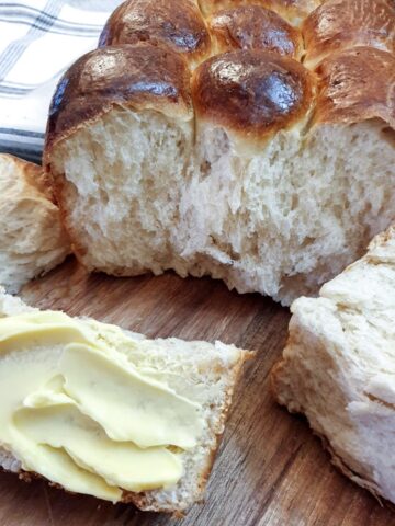 Close up of a soft condensed milk rusk (or mosbolletjie) spread with butter.