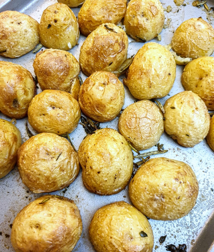 Closeup of roast potatoes on a baking tray.