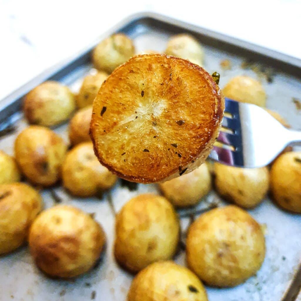 A crispy roast baby potato on a fork.