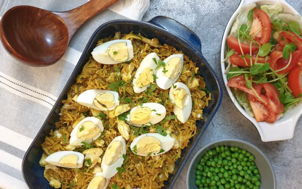 Smoked haddock kedgeree topped with hard-boiled eggs in a blue serving dish.