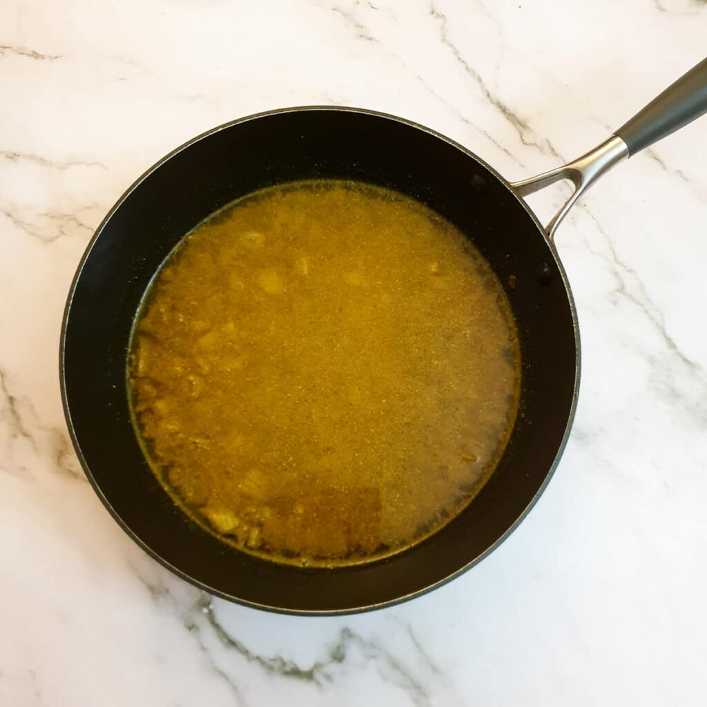 Water poured over the rice mixture in a frying pan.