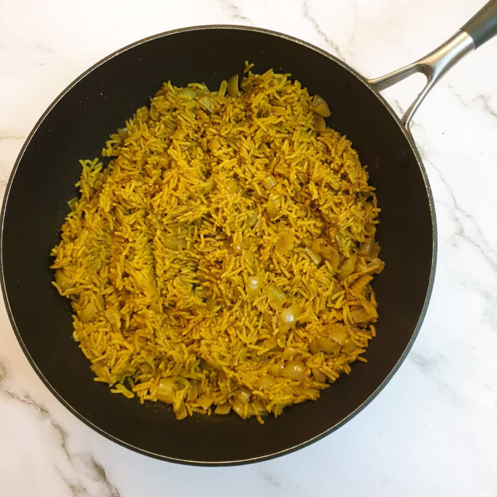 Cooked rice in a frying pan showing how the water has been absorbed.