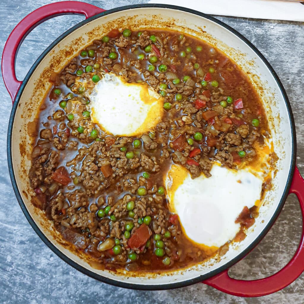 2 cooked eggs on top of a pan of lamb keema.