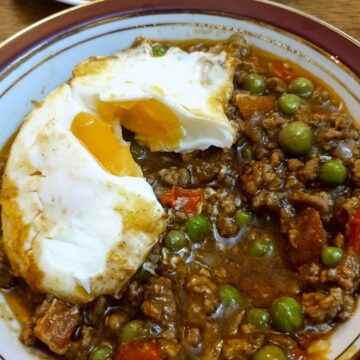 A dish of lamb keema topped with a baked egg.