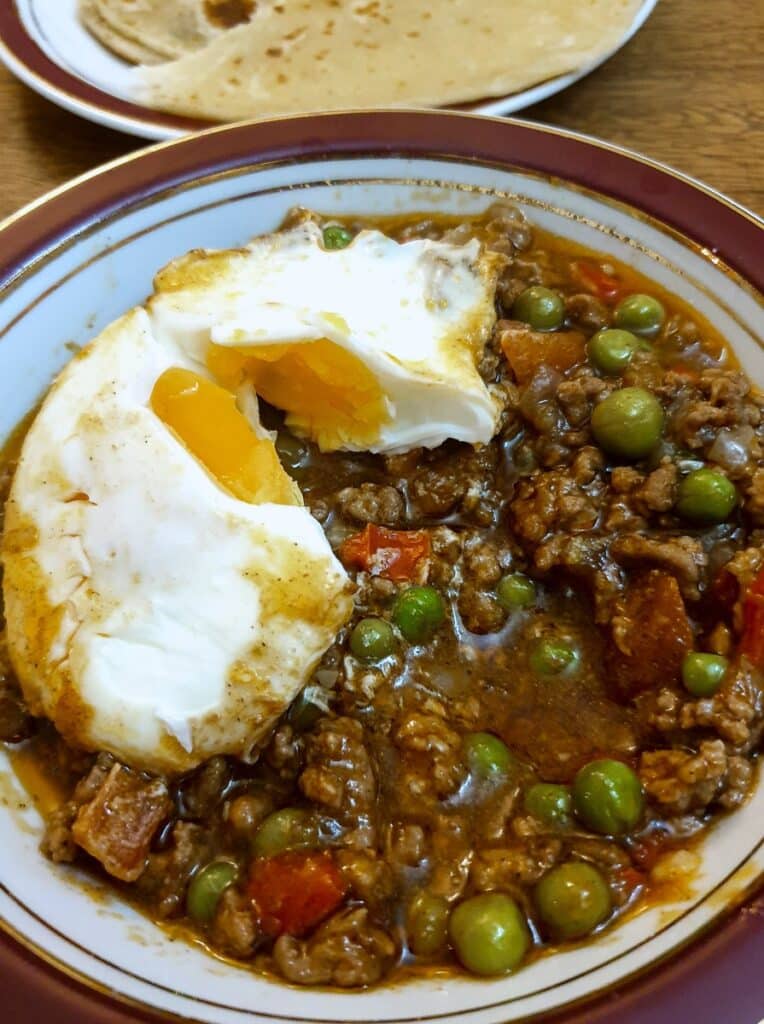 A dish of lamb keema topped with a baked egg.