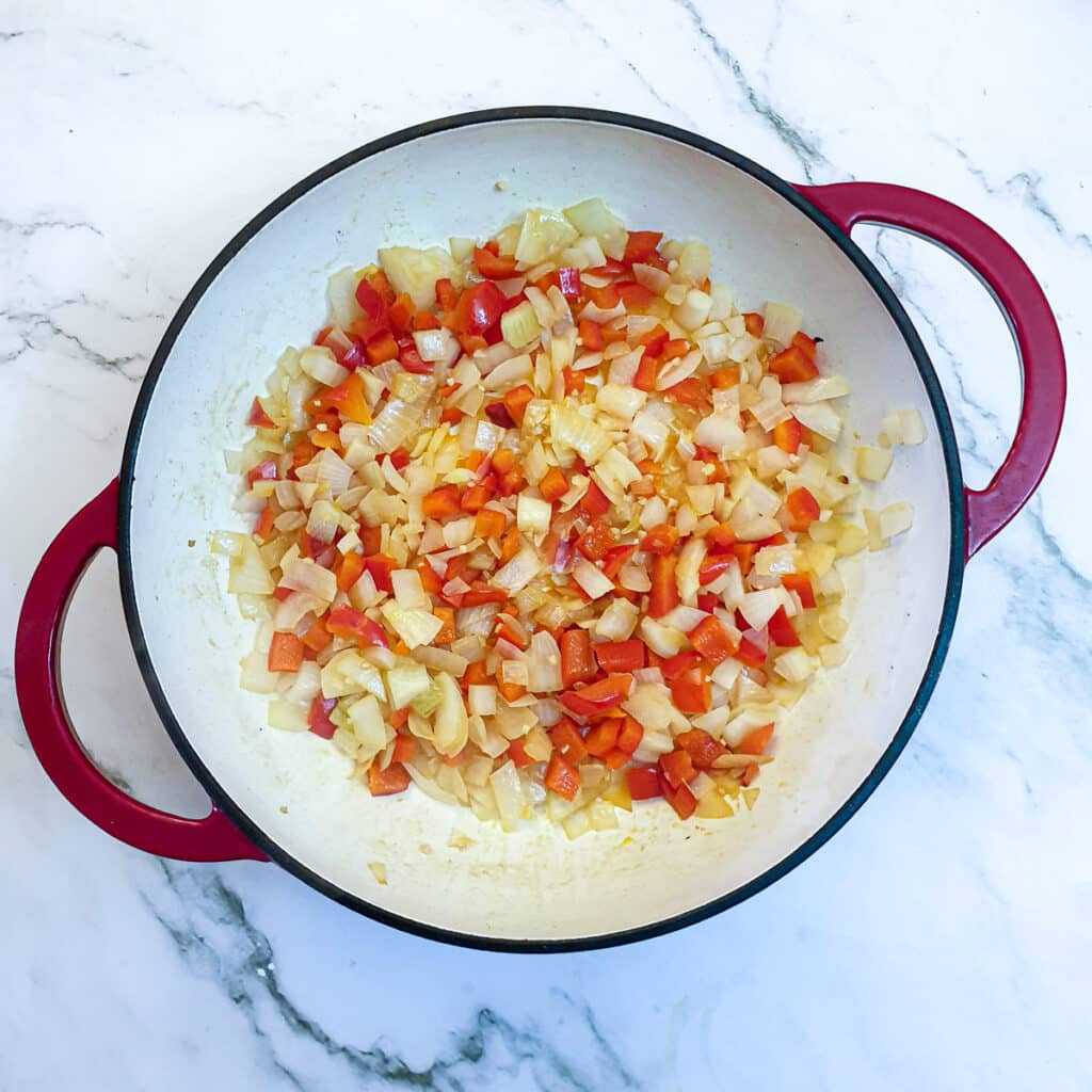 Red pepper and onions in a frying pan.