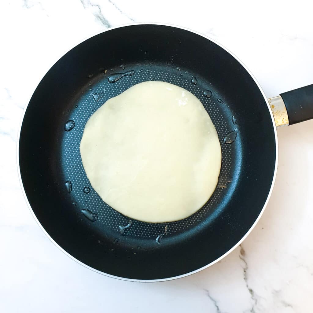 A circle of dough in a frying pan.