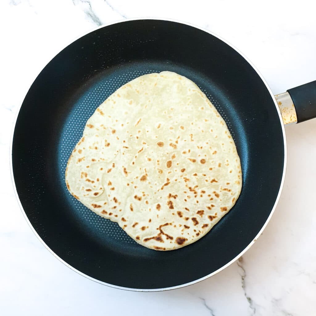 Flatbread being browned in a frying pan.