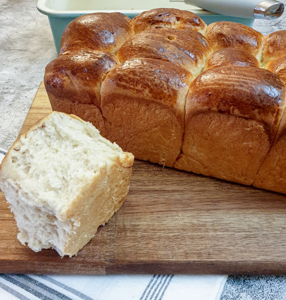 A piece of mosbolletjie in front of a loaf of baked rusks.