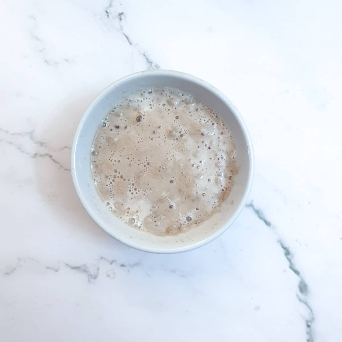 A bowl of yeast mixed with sugar and water, showing the froth that is formed when the yeast activates.