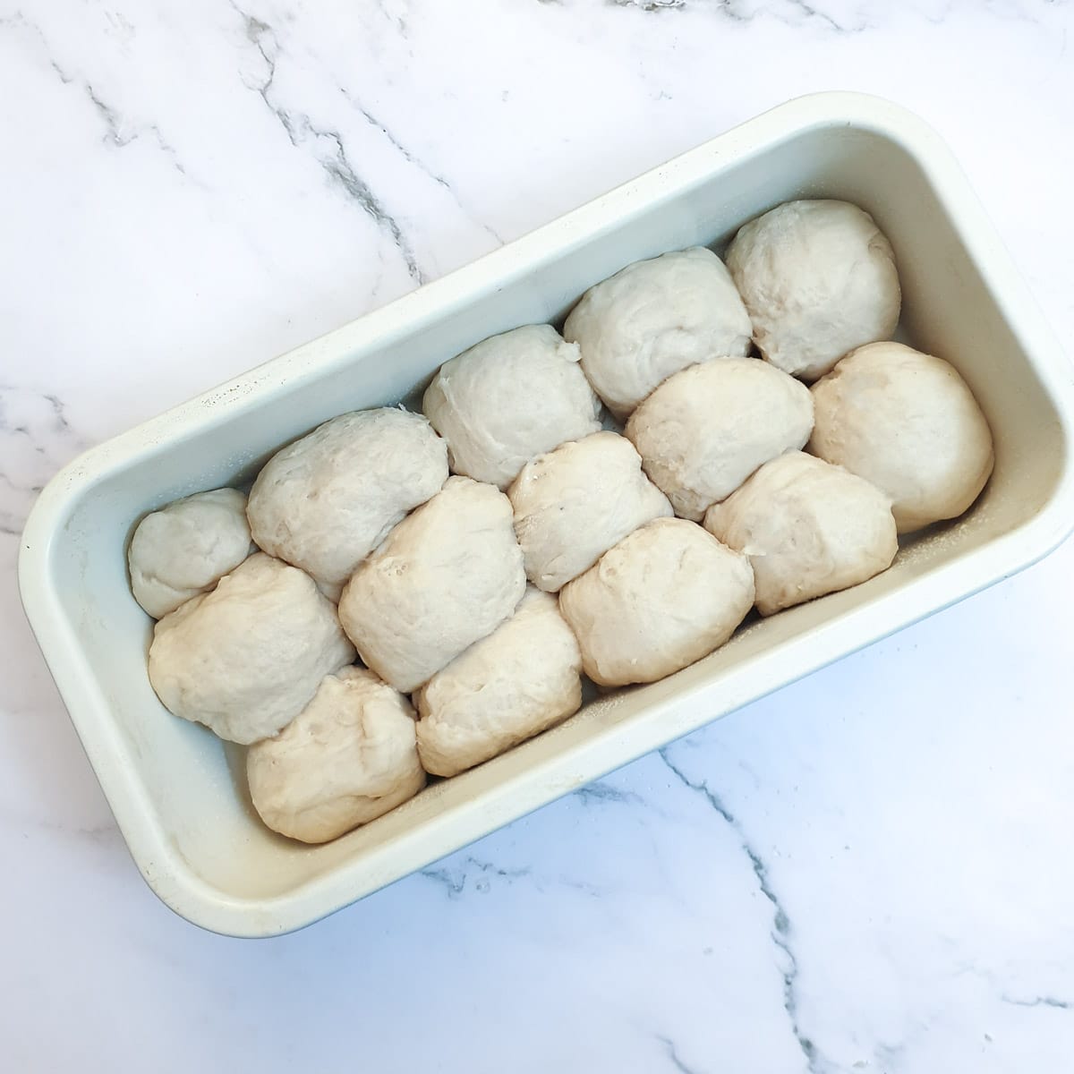 Balls of dough packed into a baking tin.