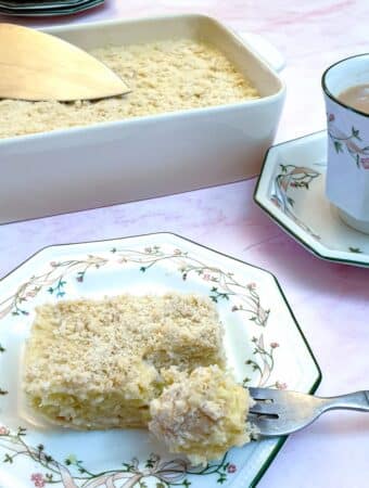 A slice of pineapple fridge tart on a plate next to a cup of tea.