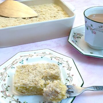 A slice of pineapple fridge tart on a plate next to a cup of tea.