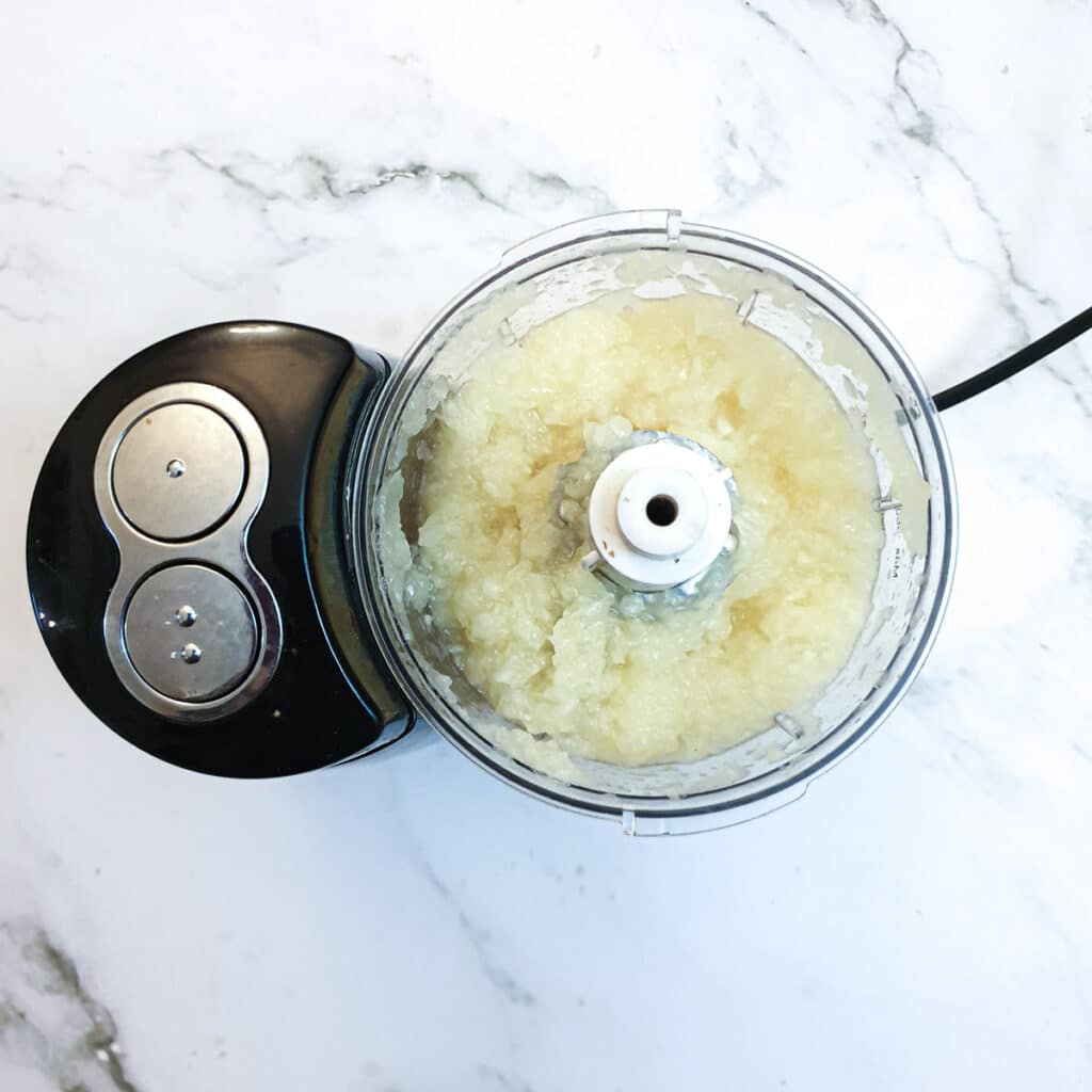 Pineapple being chopped in a food processor.