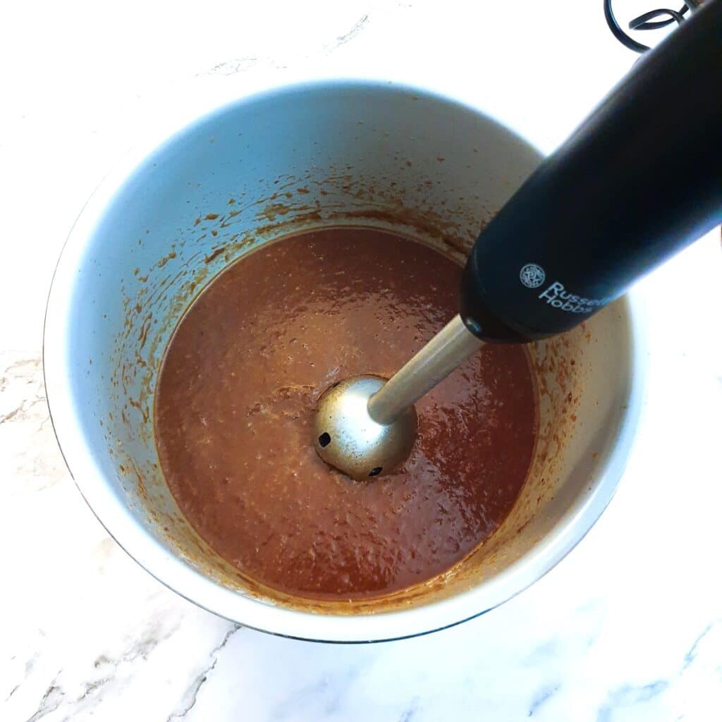 Monkey gland sauce being blended with a stick blender.