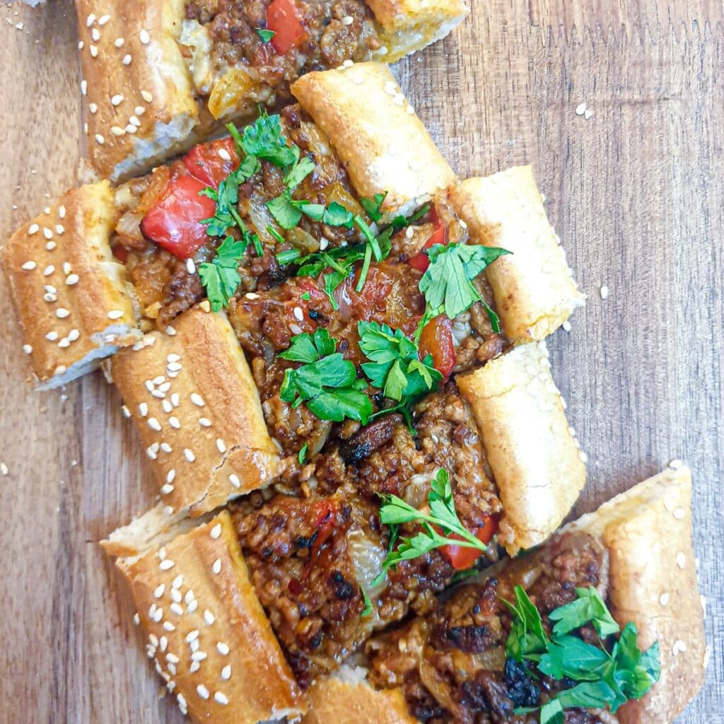 Slices of lamb pide on a wooden platter.