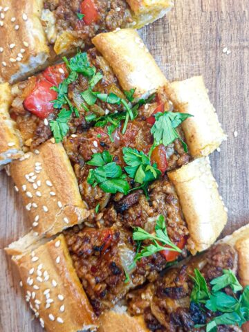 Slices of lamb pide on a wooden platter.