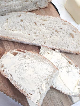 Two slices of chese and onion bread, one buttered and the other unbuttered to show the cheese and onion laminations.