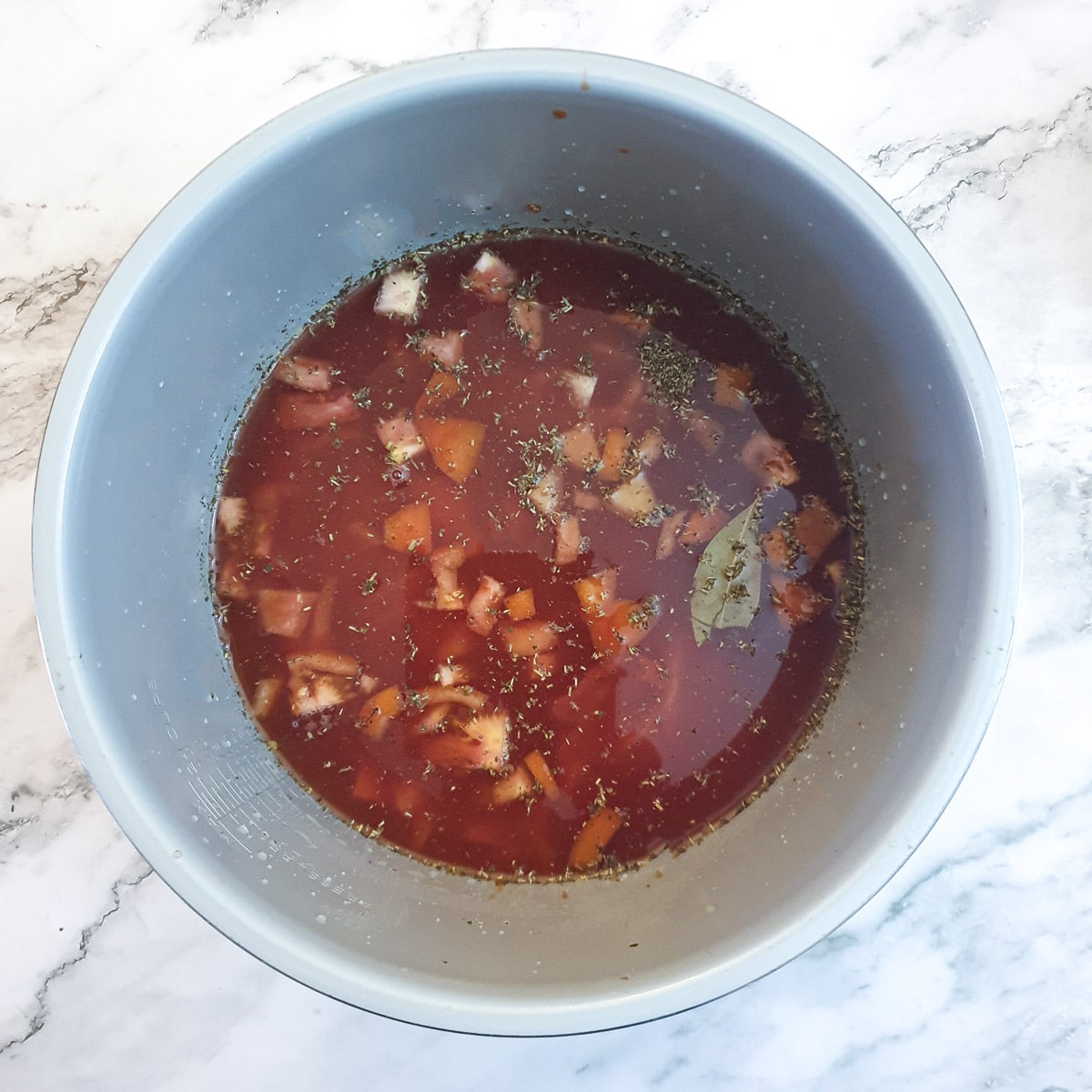 Shin beef in a pressure cooker along with passata, vegetables and herbs.