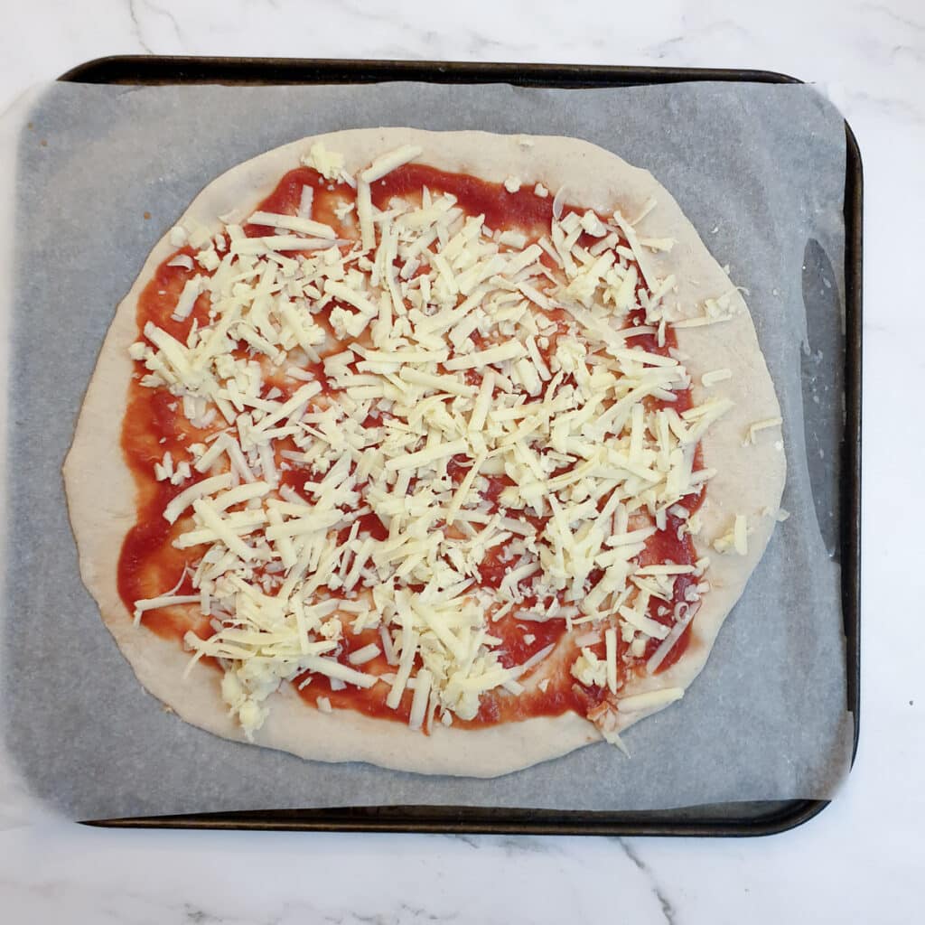 Pizza dough topped with passata and grated cheese.