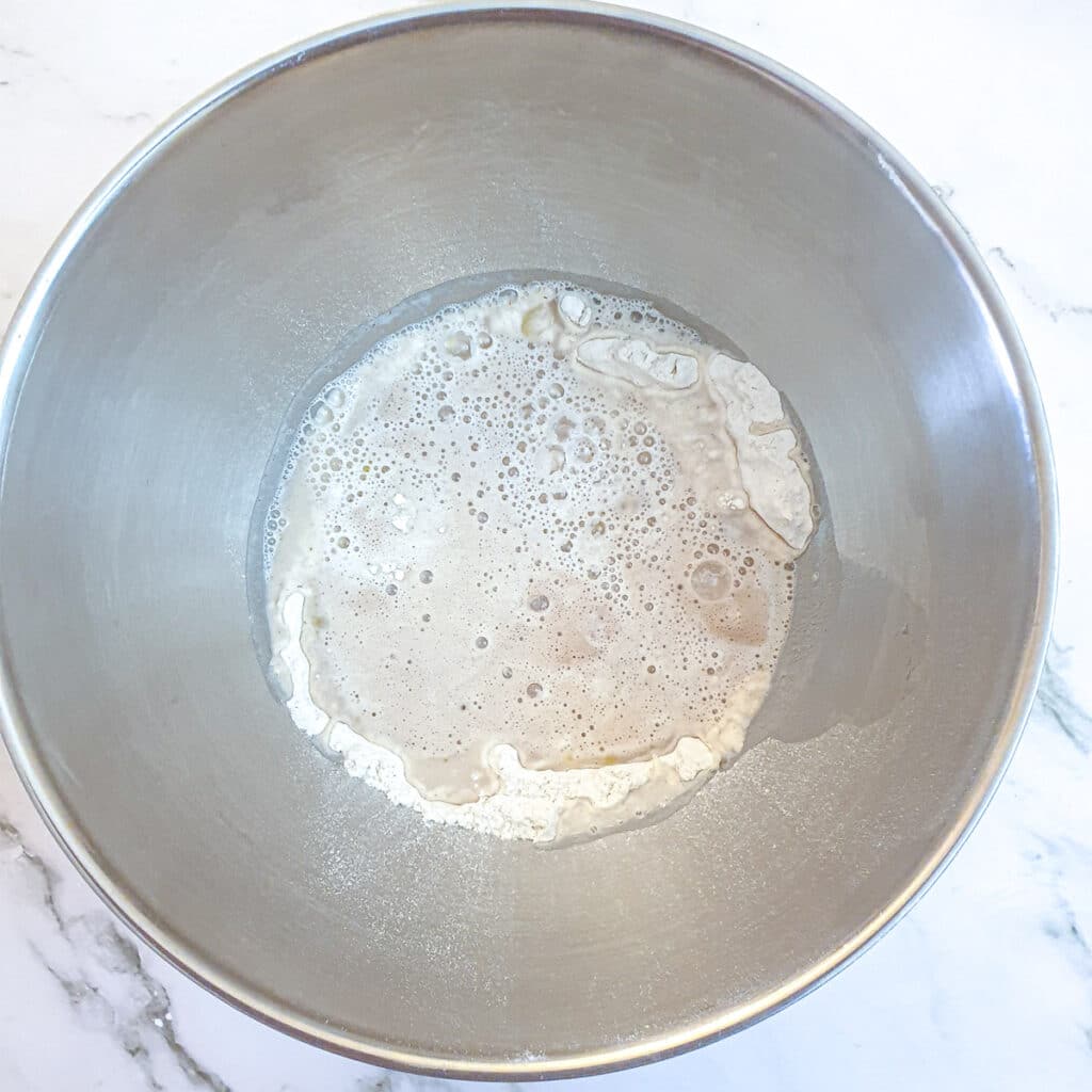 Ingredients for pizza dough in a mixing bowl.