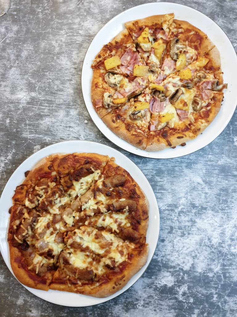 2 baked pizzas on 2 white plates.