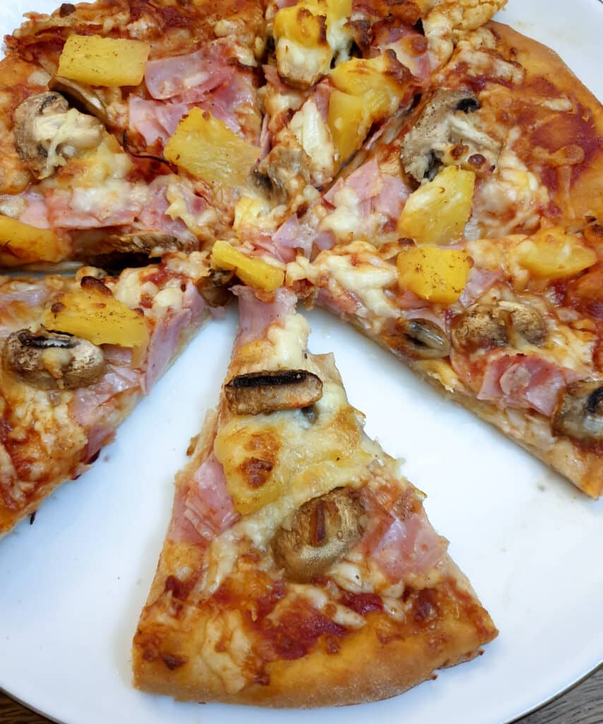 Overhead shot of a pizza cut into slices with one slice offset.